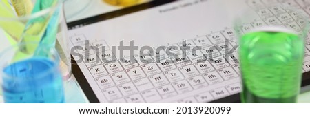 Digital tablet with periodic system of elements lying on table in laboratory closeup