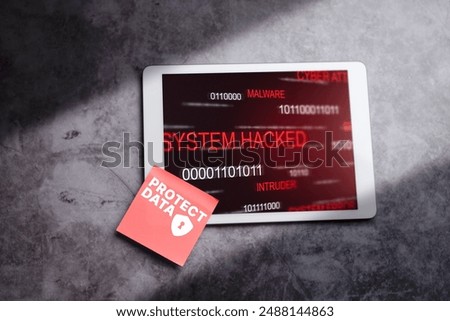 Digital tablet with red adhesive note warning. System warning hacked alert. Cyberattack on tablet. Data vulnerability, data breach. Compromised information concept.