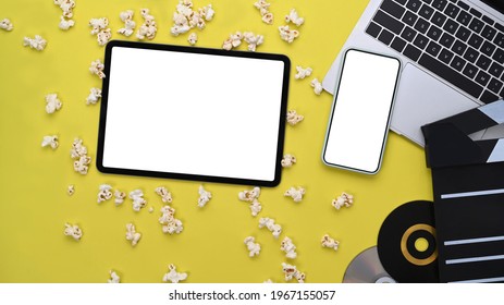 Digital Tablet, Smart Phone And Laptop Computer And Clapboard With Popcorn On Yellow Background.