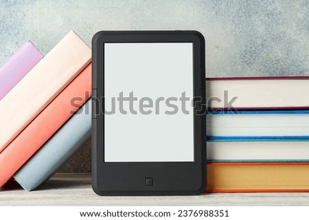 Digital tablet with a stack of books on gray background