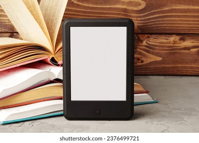 Digital tablet and stack of hardcover books against wooden background