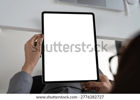 Digital tablet white screen mockup, Business woman hand holding mobile phone with blank screen while working on laptop at office.