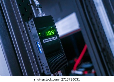 A digital temperature sensor display mounted in a rack system showcasing precise environmental monitoring. Ideal for technology and industrial applications.