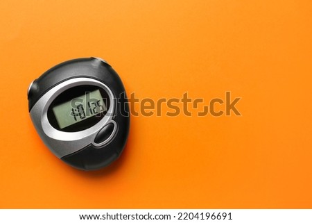 Digital timer on orange background, top view. Space for text