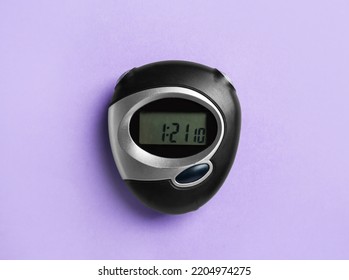 Digital timer on violet background, top view