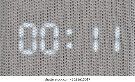 Digital timer showing 01:00 minutes displayed through mesh textile surface, time lapse. Macro shot of illuminated electronic countdown digits. Technology and timekeeping concept