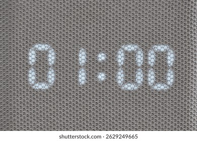 Digital timer showing 01:00 minutes displayed through mesh textile surface. Macro shot of illuminated electronic countdown digits. Technology and timekeeping concept for design and print