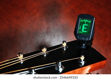 a digital tuner for adjusting the strings on the head of a guitar neck - Powered by Shutterstock