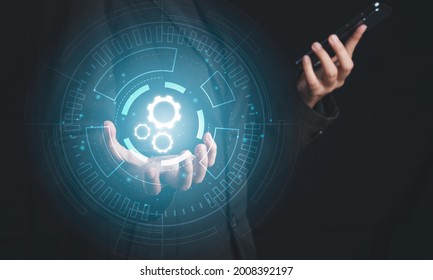 Digital workflow, Digital transformation, Automatic technology concept. Businessman holding digital machine gears  icons in cyber circle and holding smartphone.