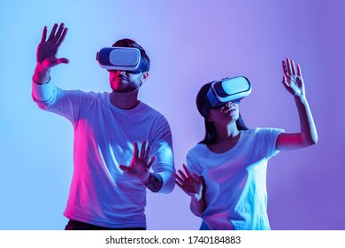 Digital world. Couple in virtual glasses make hands movements isolated in neon, studio shot - Powered by Shutterstock