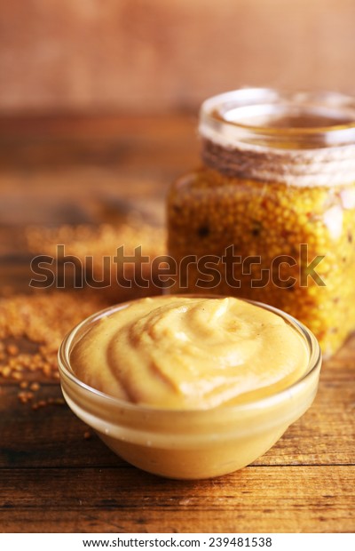 Dijon Mustard in glass jar and mustard sauce\
in glass bowl on wooden\
background