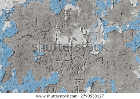 Dilapidated interior featuring a decaying blue and grey plastered wall, weathered concrete background