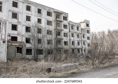 Dilapidated residential building with empty windows, collapsed roof
