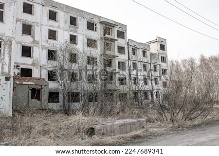 Dilapidated residential building with empty windows, collapsed roof