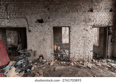 Dilapidated room inside abandoned structure featuring rubble, scattered trash, damaged brickwork, and empty doorways revealing nature outside in realistic decayed state