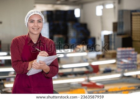 Diligent female worker takes inventory of ripe tangerines on a packing line.