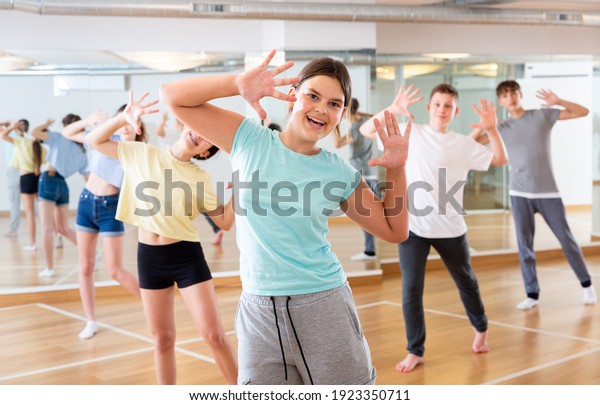 Diligent friendly smiling teenagers learn dance
movements in dance
class