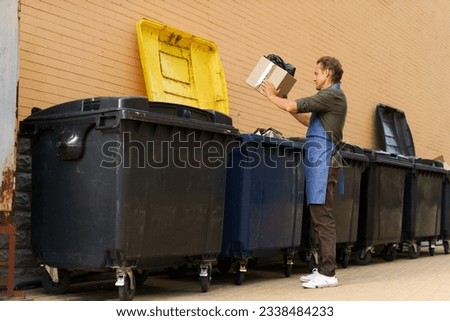 Diligent kitchen worker or waiter is seen responsibly disposing of garbage in city trash can. With sense of responsibility and cleanliness, he ensures proper waste management in urban environment