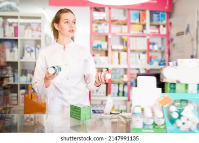 Diligent pleasant positive female druggist in white coat working in pharmacy