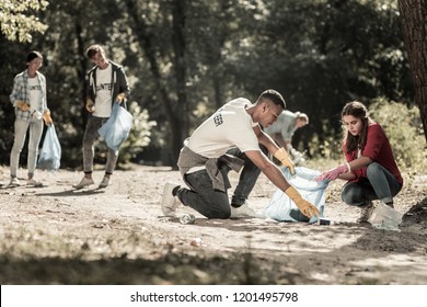 Diligent Volunteers. Company Of Diligent Volunteers Working Hard While Cleaning Up The Trash Left In Forest