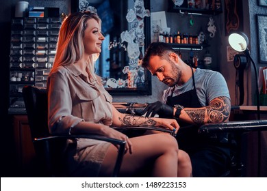 Dilligent Focused Tattoo Artist Is Creating New Tattoo On Young Woman's Hand At Tatoo Studio.