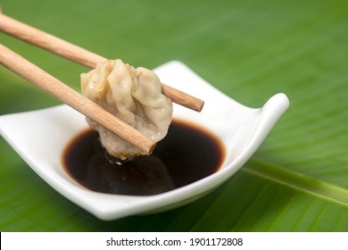 dim sum pork when immediately dipped into the sauce, Close up with blurred background . dimsum or dumpling is a snack from China