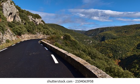 Diminishing perspective of country road D942 above canyon Gorges de la Nesque in the Vaucluse Mountains in Provence region, France on sunny day in fall season with stone wall and colorful trees. - Shutterstock ID 2104063958