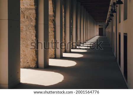 Diminishing perspective view of fortress passageway with arches columns and row of antique lanterns on the wall. Portal with light and shadows in ancient eastern bastion.Corridor archway perspective