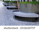 Diminishing view of public recreation area with empty contemporary round shaped benches and potted plants as modern city architecture design concept near business centre. Urban public furniture.