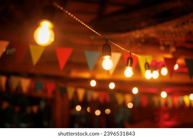 A dimly lit bar decorated with colorful flags and string lights - Powered by Shutterstock