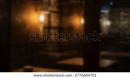 A dimly lit interior scene featuring warm, inviting lighting and a blurred background, creating a sense of intimacy and comfort. The image captures the ambiance of a cozy space.