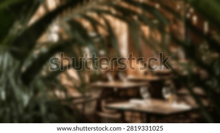 A dimly lit restaurant interior featuring tables and chairs surrounded by abundant tropical plants and soft ambient lighting.