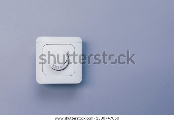 Dimmer Light Switch. Electrician switch.\
White rolling electricity switch on bright\
wall