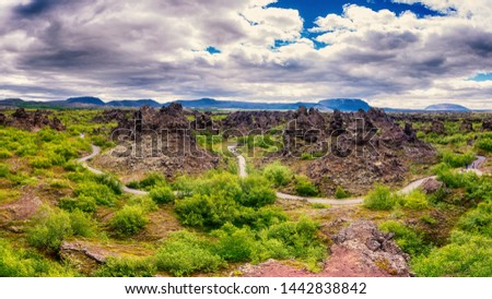 Dimmuborgir lava fields near Myvatn in Iceland. Amazing nature landscape, panoramic view of popular tourist attraction - green valley, rock formations and blue cloudy sky, outdoor travel background