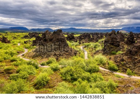 Dimmuborgir lava fields near Myvatn in Iceland. Amazing nature landscape, panoramic view of popular tourist attraction - green valley, rock formations and blue cloudy sky, outdoor travel background