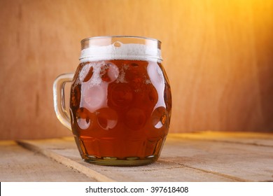 Dimpled Mug With Amber Beer On A Grunge Wood Surface