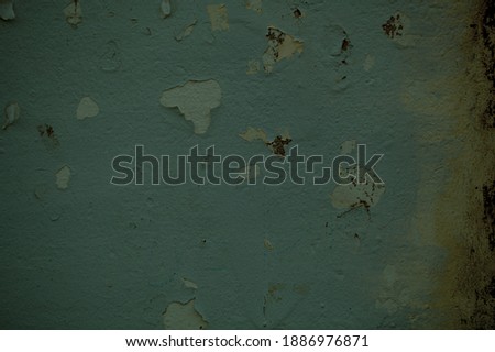 Dingy green wall background texture with damp stains and peeling paint in a full frame view
