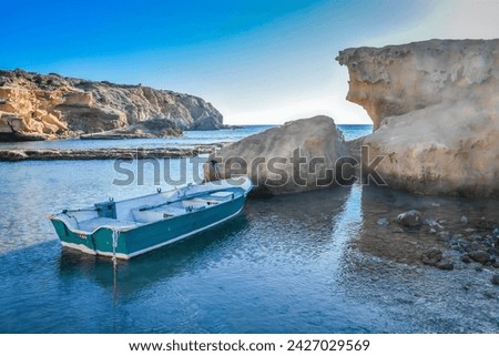 Dingy tied to rocks in a sheltered position at the western end of beautiful Firiplaka Beach on the southern coast of the Greek island of Milos.