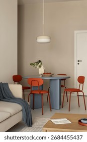 Dining area with round blue table, orange chairs and pendant lamp in a modern neutral interior.