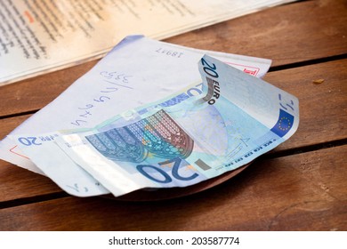 Dining check with Euro banknotes on wooden table.