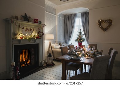 Dining room of a home decorated for Christmas. The table is set ready for Christmas dinner and the fire and candles are lit.  - Powered by Shutterstock
