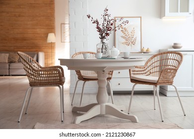 Dining room interior with tea set on round table and wicker chairs