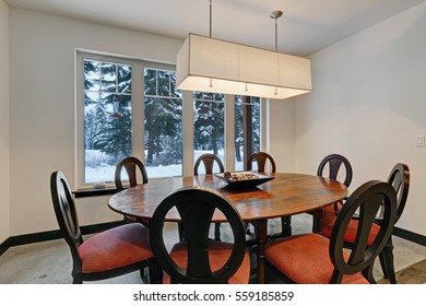 Dining room with round wood dining table and upholstered chairs with red cushions. Northwest, USA