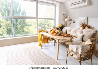 Dining table with autumn setting and pumpkins in room