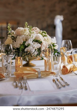 Dining table with beautiful table settings and floral decorations. Beautifully decorated table in a restaurant. Silver cutlery, lit candles and clear glasses decorate the table in a restaurant