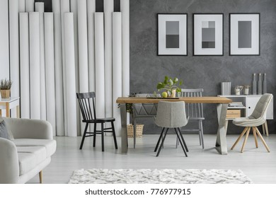 Dining Table And Chairs In Monochromatic Living Room With Paper Tubes Decoration And Posters On Textured Wall