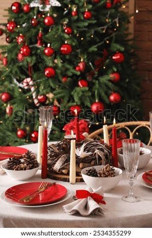 Dining table with Christmas setting and burning candles in room, closeup