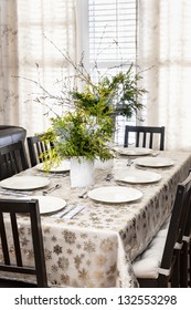 Dining Table Decorated For Christmas With Eight Place Settings And Evergreen Centerpiece