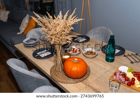 Dining table decorated with pampas grass and pumpkin, serving various appetizers