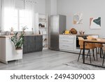 Dining table in interior of kitchen with fridge and counter